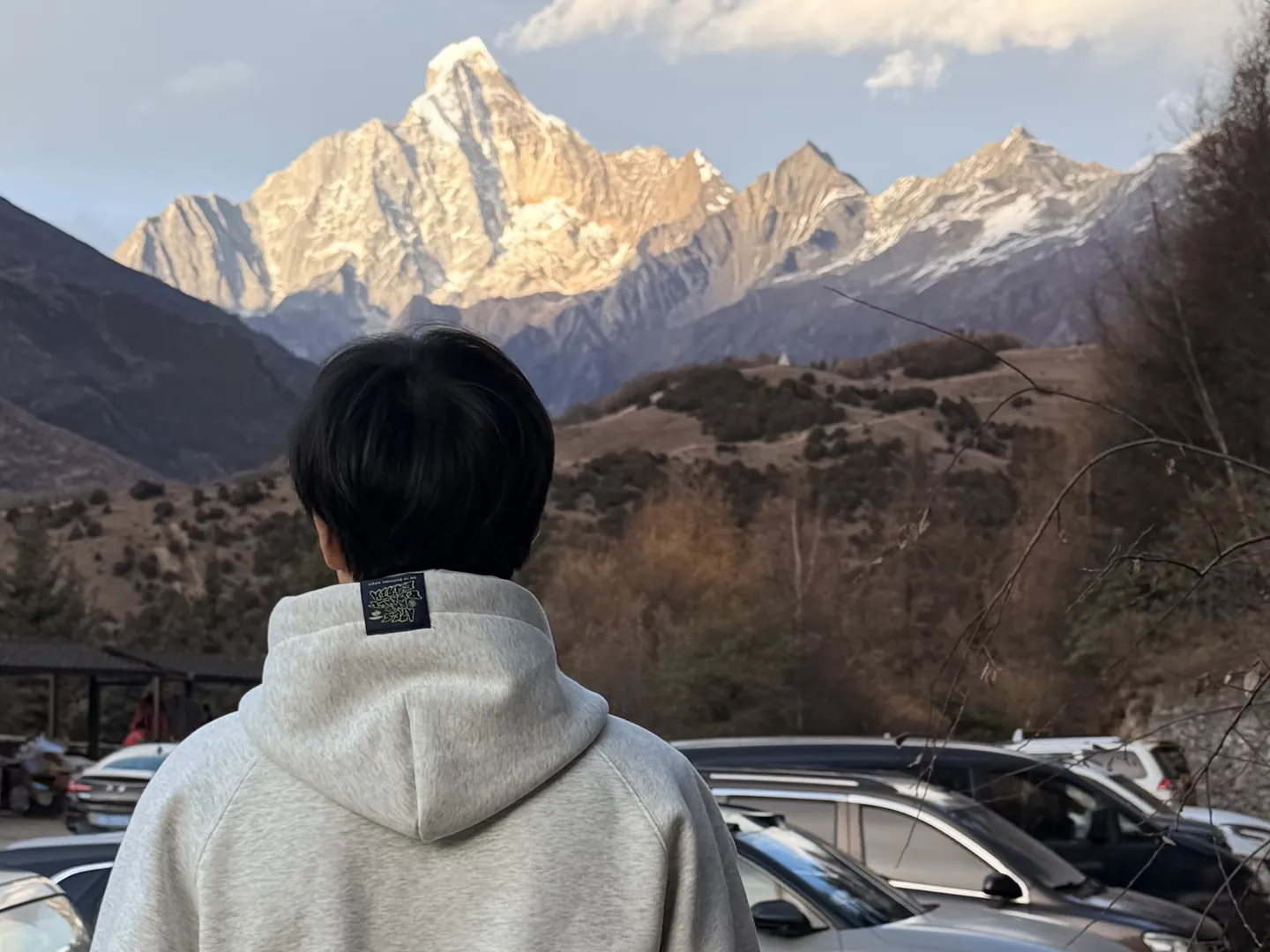 Bo Lan, seen from behind, looking at a snow peak lit by evening sun