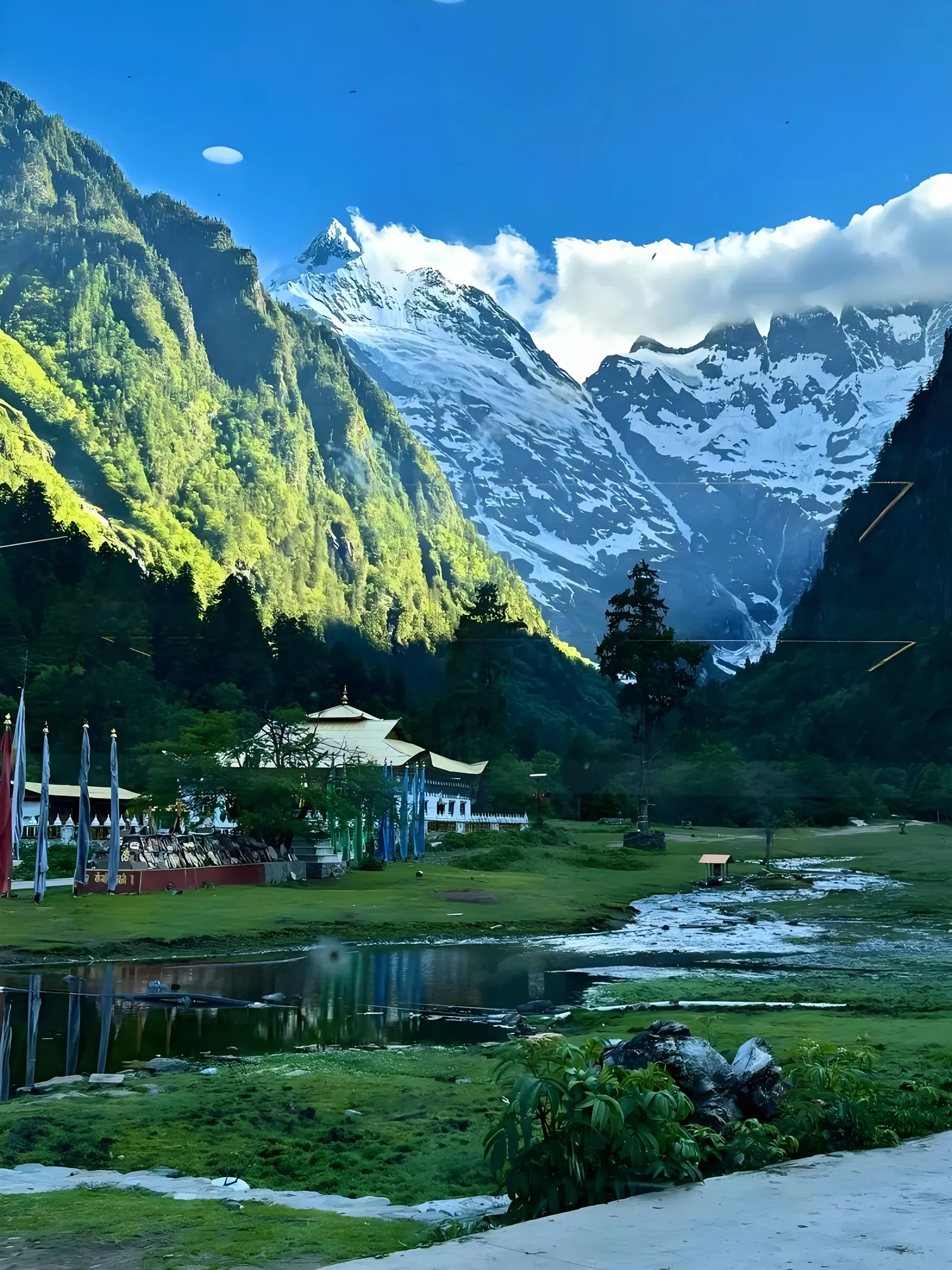 Snow mountain above a green valley and stream in northwest Yunnan