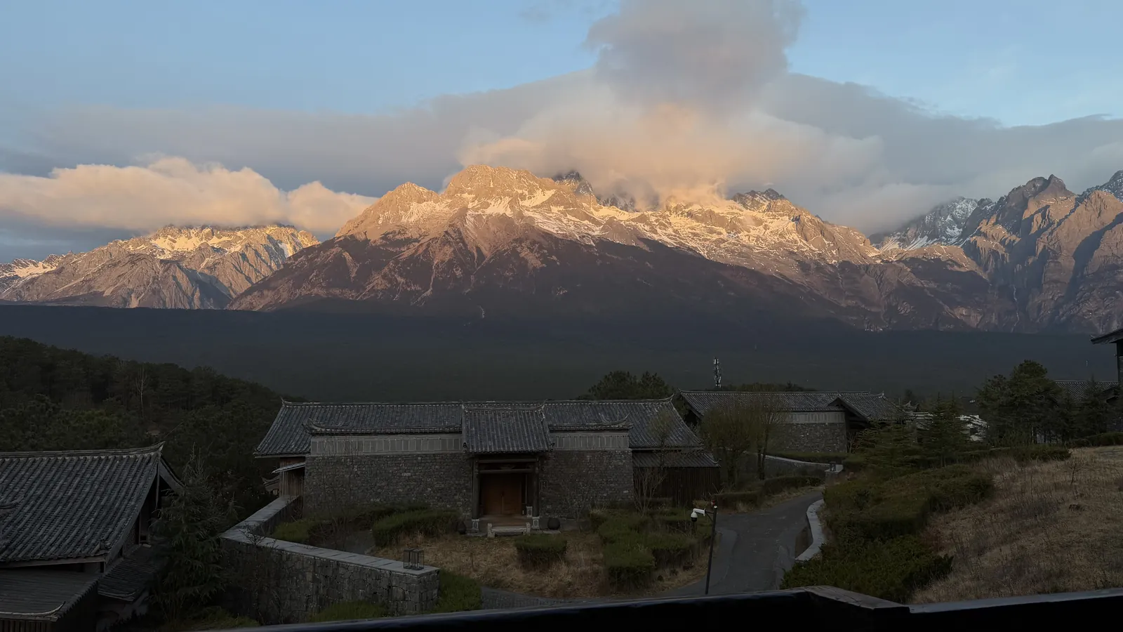 Jade Dragon Snow Mountain catching the first sun above stone-roofed houses