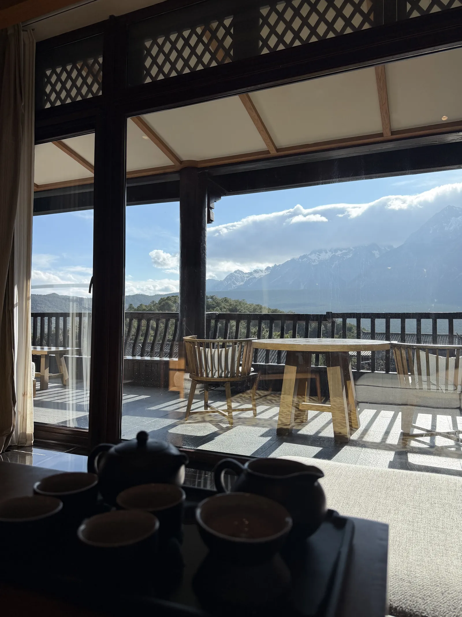 A tea set on a wooden terrace with snow peaks across the valley